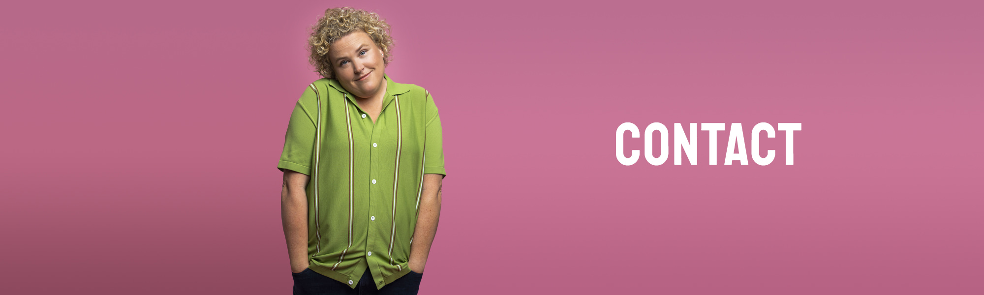 Comedian Fortune Feimster in front of a pink background wearing a green sweater.